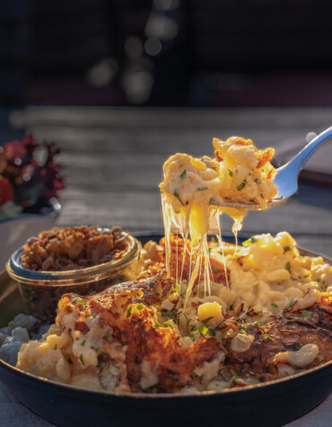 A pan of cheesy pasta with a side salad on a rustic wooden table.