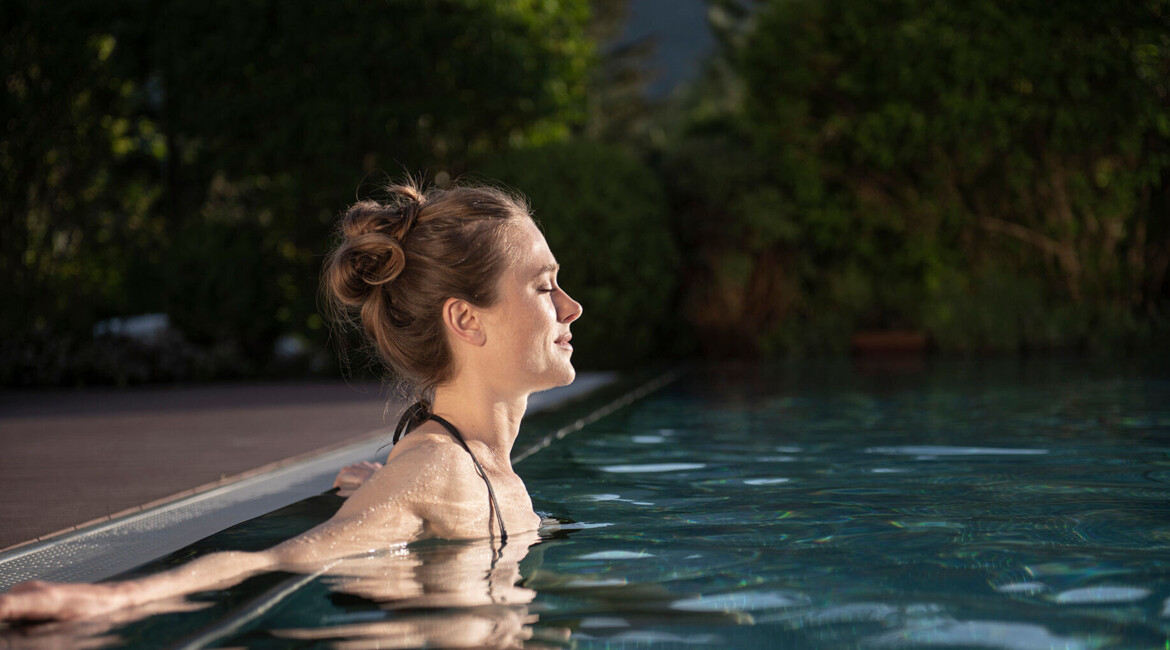 Woman relaxing in the outdoor pool of Waldhof Fuschlsee Resort