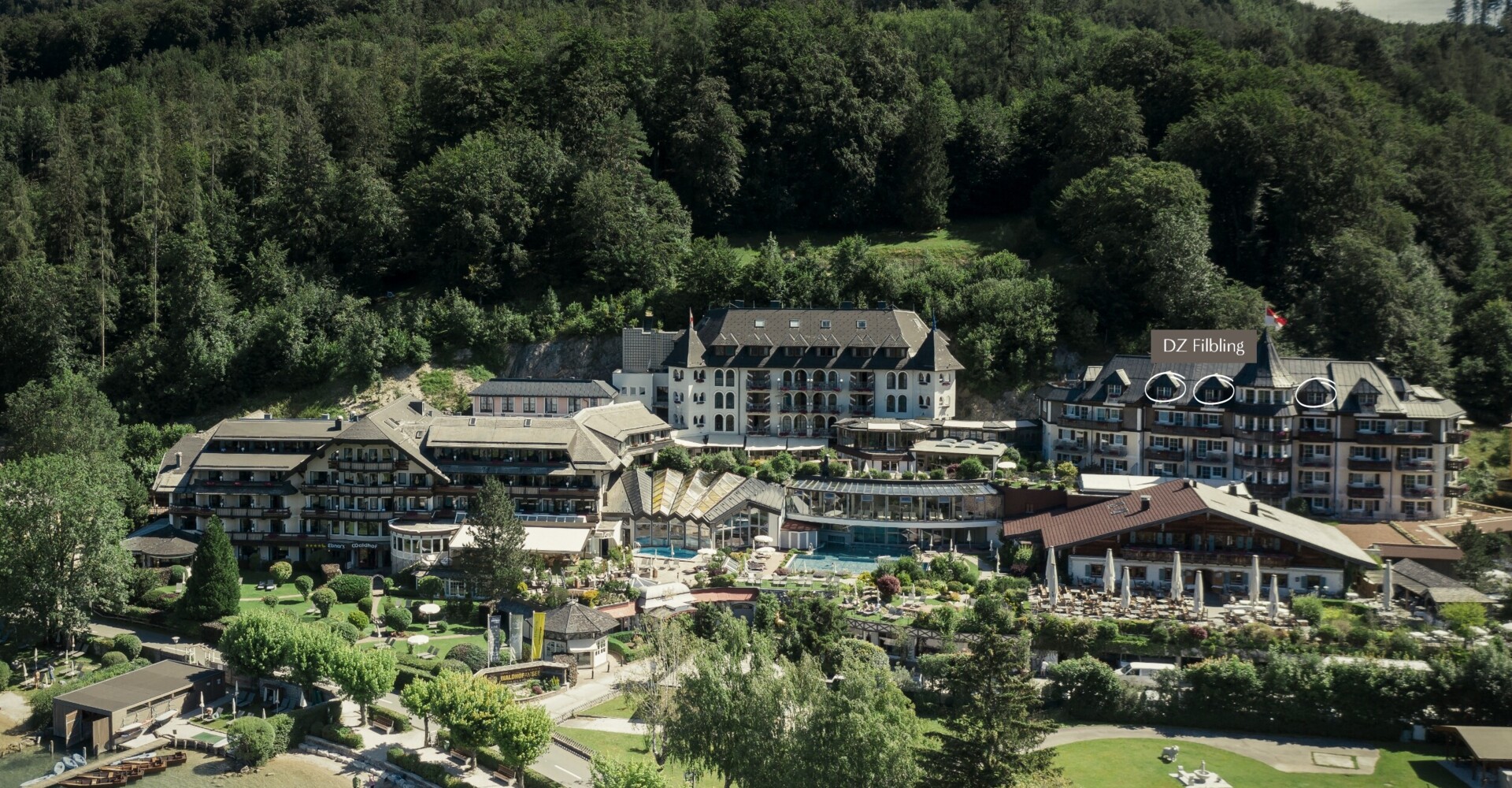Luftaufnahme vom Waldhof Fuschlsee Resort mit Pool und Garten am Ufer des Fuschlsees.