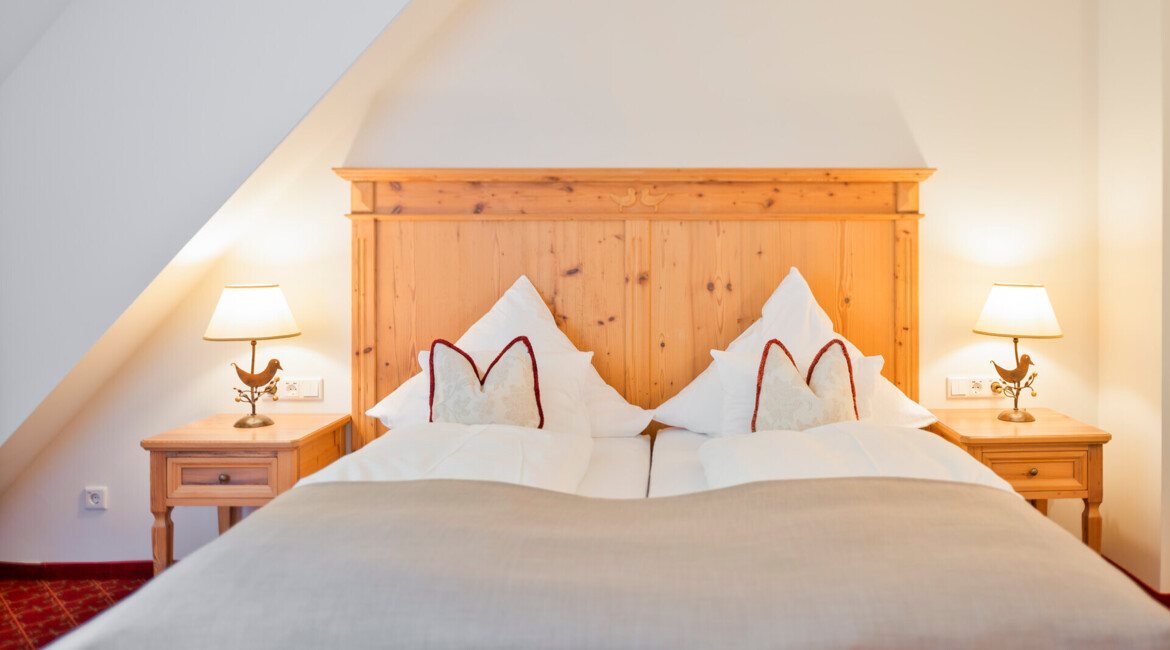 Großzügiges Doppelbett mit Holz in der Osterhornsuite des Hotels Waldhof Fuschlsee Resorts.