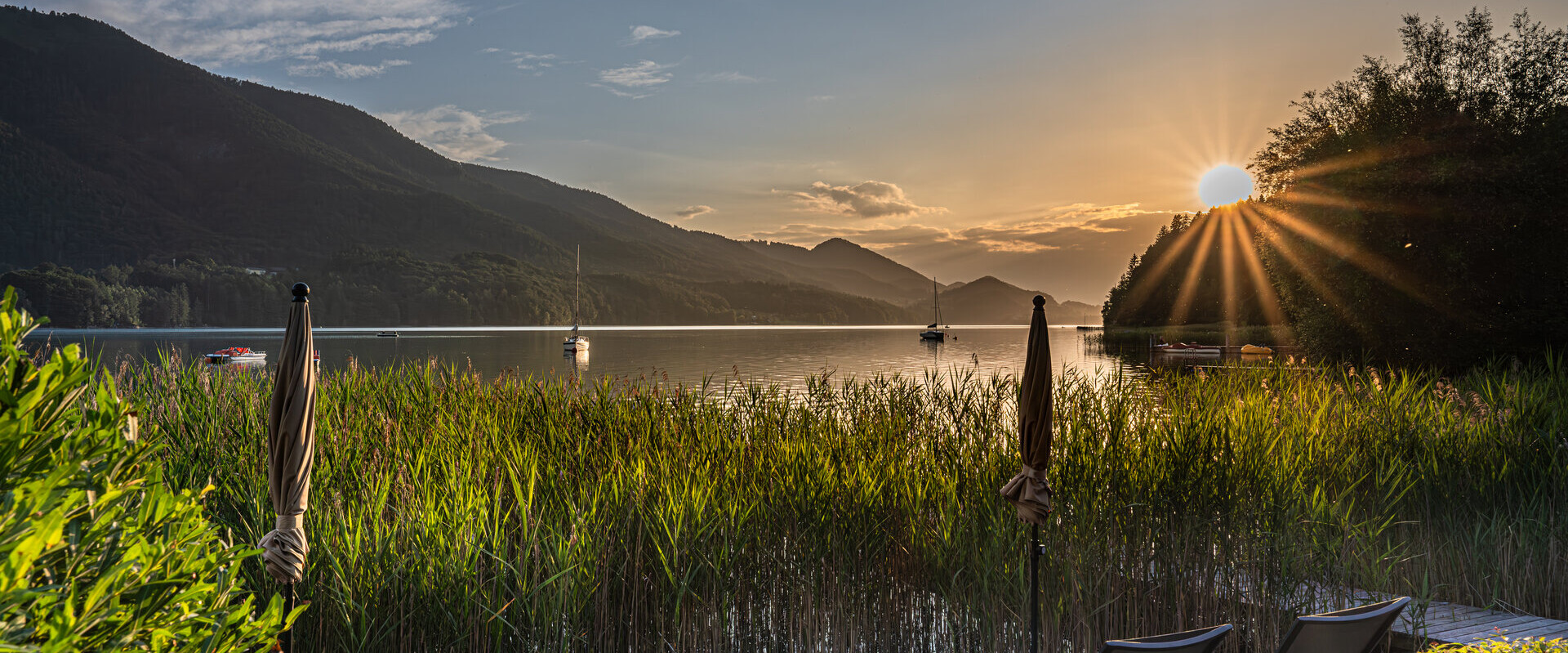 Sunset at the private bathing beach of the Waldhof Fuschlsee Resort, golden atmosphere, calm lake with shrubs