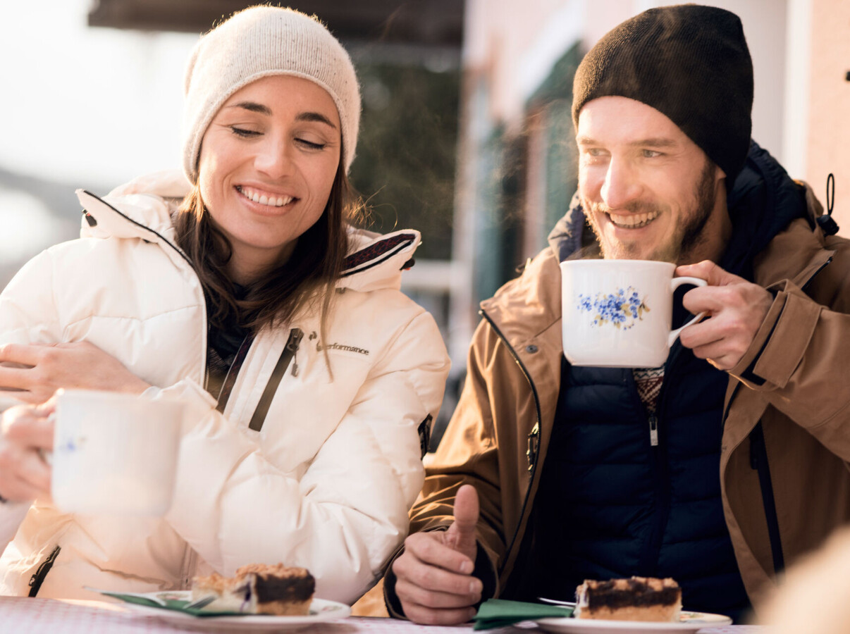 Pärchen auf der Waldhofalm mit einem Heißgetränk und Kuchen.