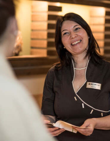 A smiling staff member at a reception desk, engaging with a guest.