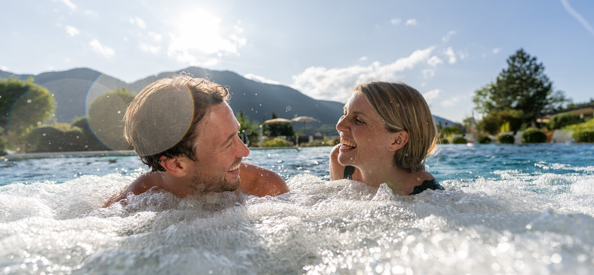 Pärchen im Außenpool, beide lachen und haben Spaß.