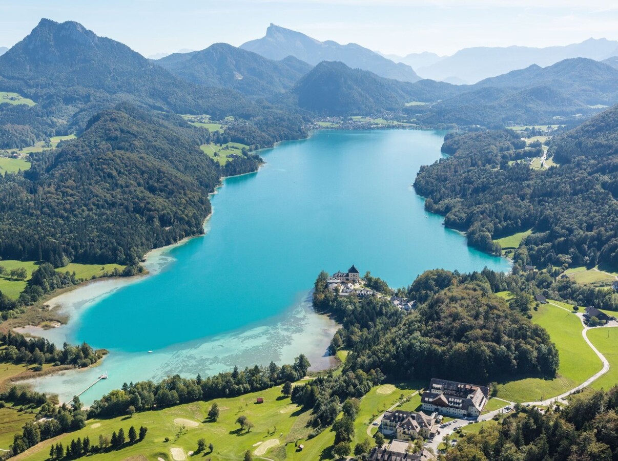 Panoramablick auf den türkis-grünen Fuschlsee im Sommer von oben.