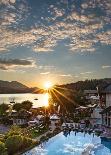  Sonnenuntergang über dem Fuschlsee im Sommer mit Blick auf den Wellnessbereich des Hotel Ebner's Waldhof am See.