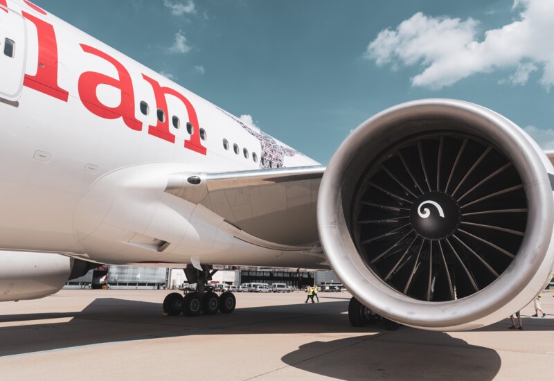 Close-up of an airplane engine on the tarmac under a blue sky.