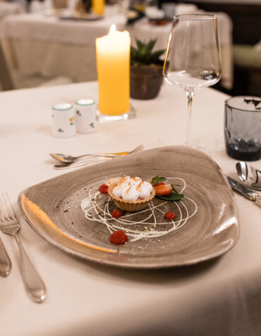 Elegant dessert on a unique plate, elegantly set table with candlelight ambiance in a sophisticated restaurant setting.