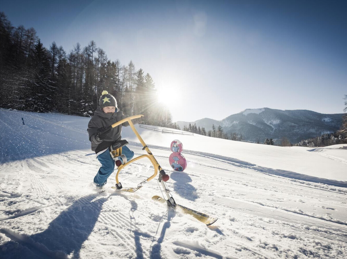 Kind auf einem Snowbike auf der Waldhofalm am Fuschlsee.