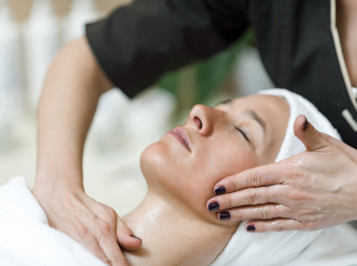 A person receiving a relaxing facial massage at a spa, wrapped in a towel.