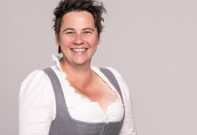 A person smiling in traditional attire, representing the Waldhof Fuschlsee Resort's welcoming atmosphere.