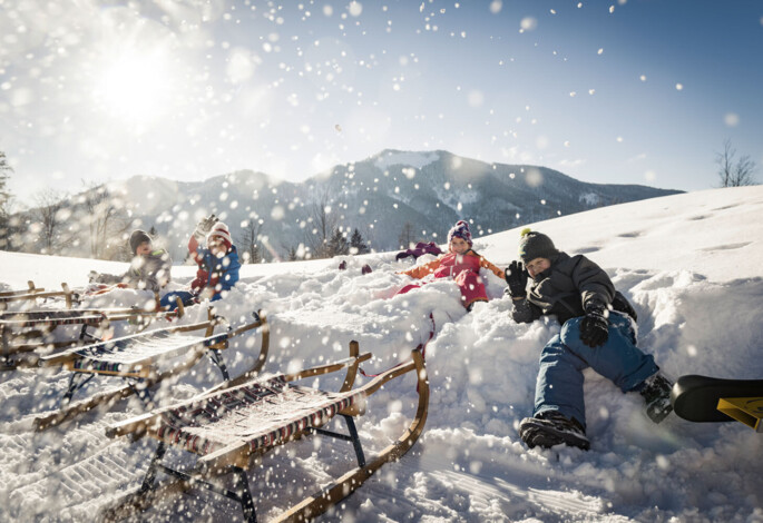 Children playing in the snow with sleds on a sunny winter day.