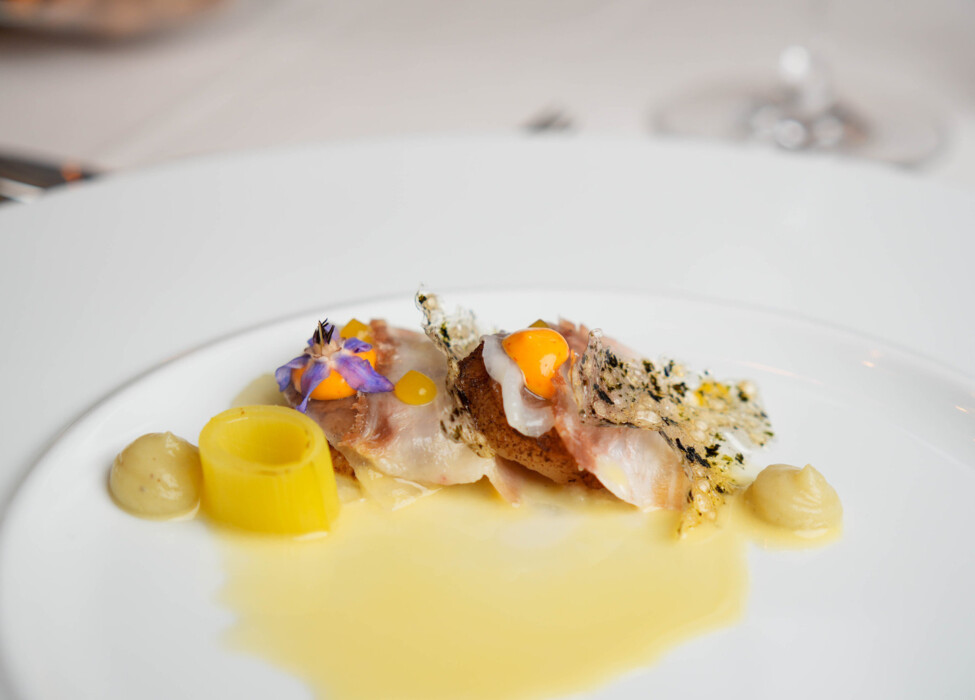 A beautifully plated gourmet dish with artistic garnish and delicate presentation on a white plate.