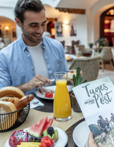 Junger Mann beim Frühstück im Gourmethotel Ebner's Waldhof am Fuschlsee.