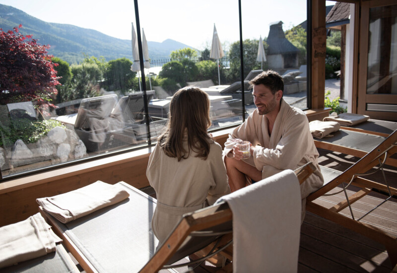 Pärchen sitzend im Ruheraum mit Blick auf den Fuschlsee im Wellnesshotel Ebner's Waldhof im Salzburger Land.