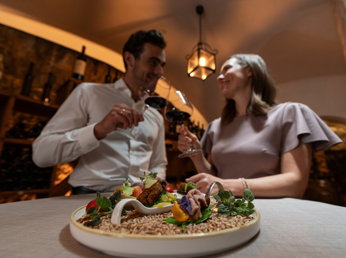Pärchen beim Anstoßen mit einem Glas Wein im Waldhof Fuschlsee Resort.