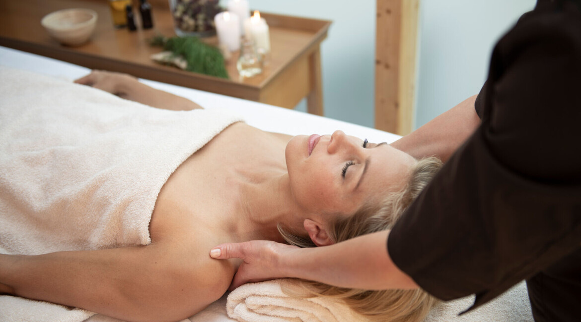 A person receiving a relaxing massage at a spa, with candles and natural elements in the background.