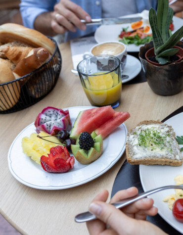 A table with a breakfast spread of scrambled eggs, fresh fruit, bread, and juice, set in an inviting atmosphere.