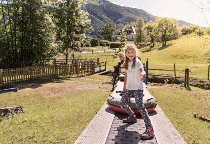 Kinder mit Tubing-Reifen auf dem Förderband im Familienurlaub am Fuschlsee.