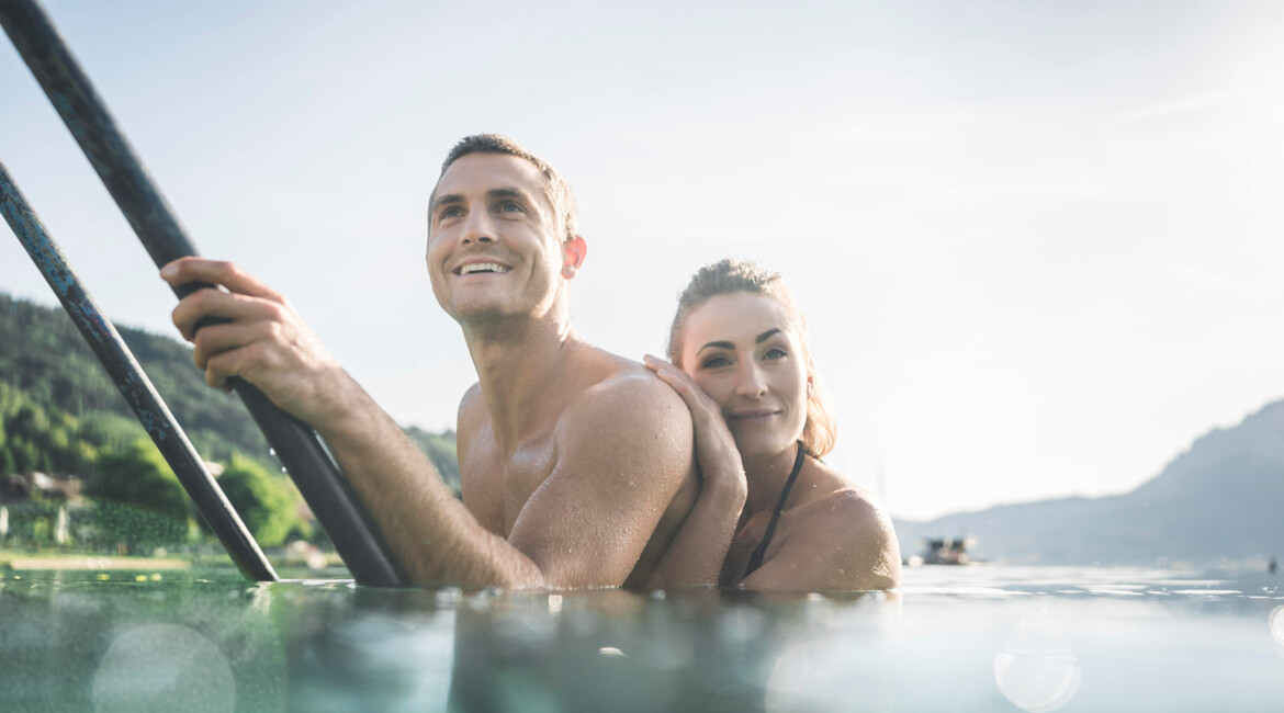 A couple enjoys a scenic paddle in a lush lake setting, smiling and relaxed.