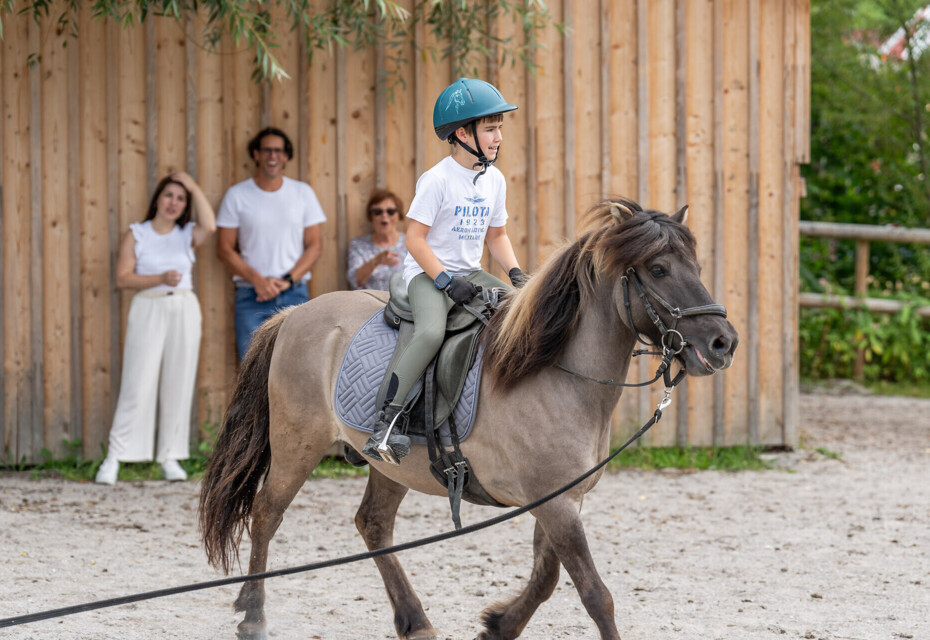 Großeltern sitzen mit der Enkelin am Strand des Fuschlsees und lassen Seifenblasen steigen.